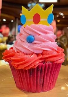 a cupcake with pink frosting and a crown on top