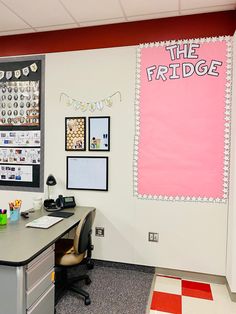 an office cubicle with a desk, chair and bulletin board on the wall that says the fridge