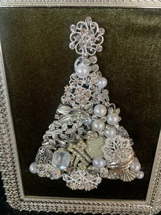 a christmas tree made out of pearls and other items in a silver frame on a black background