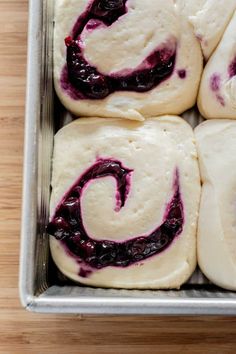 rolls with blueberry filling in a metal pan on a wooden counter top, ready to be baked