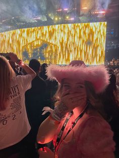 a woman covering her face while standing in front of a stage with fireworks and lights