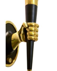 a black and gold hand holding onto a wall light