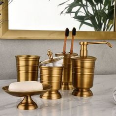 gold bathroom accessories set with soap dispenser and toothbrush holder on marble countertop