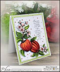 a card with some fruit on it and flowers in the background, sitting on a table