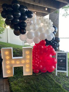 balloons and letters are hanging from the ceiling in front of a sign that says h