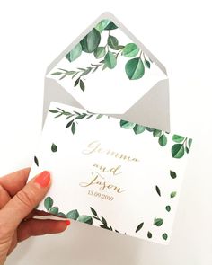 a hand holding an envelope with greenery on it