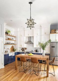 a kitchen with wooden floors and white cabinets is pictured in this image, there are three chairs at the center of the table