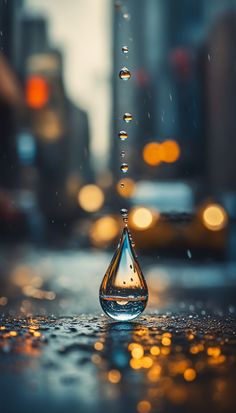 a drop of water that is sitting on the ground in front of some buildings and cars