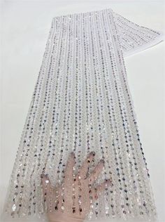 a hand reaching out from behind a sheered curtain with sequins on it