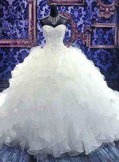 a white wedding dress on display in front of a blue wall