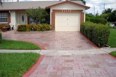 a house with a driveway in front of it that has a red brick walkway leading up to the garage