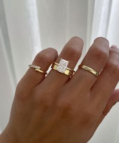 a woman's hand with two gold rings and one diamond ring on her finger