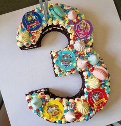 a birthday cake shaped like the number 3 with decorations on it's top and bottom