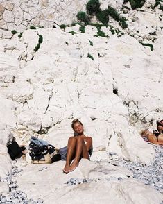 a woman sitting on top of a rock covered hillside