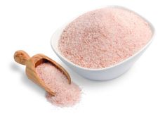 a white bowl filled with pink sugar next to a wooden spoon