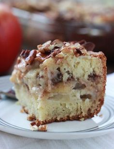 a close up of a piece of cake on a plate with an apple in the background