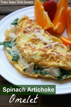 spinach artichoke omelet on a white plate with oranges and strawberries