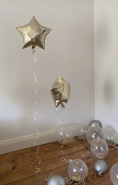 balloons and streamers in the shape of stars on a wooden floor next to a wall