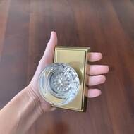 a person's hand holding an empty glass in front of a door knob on a wooden table