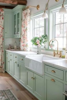 a kitchen with green cabinets and floral curtains