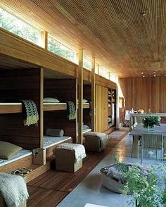 a room filled with bunk beds next to a table and chairs in front of a wooden wall