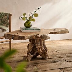 a wooden table topped with a green vase filled with flowers sitting on top of a hard wood floor