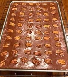 a pan filled with chocolate and pecans sitting on top of a wooden table next to a wire rack