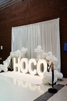 the word hoco is lit up in white balloons