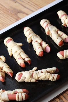 hot dogs wrapped in bacon are on a baking sheet and ready to be baked into buns