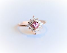 "Pretty in pink! This luxurious handmade cluster ring features one round natural Sri Lankan pink sapphire in the middle, surrounded by a sparkling bouquet of side diamonds. Customize this handmade ring and make it unique just for you: choose your favorite premium metal from the menu and create a stunning halo cluster ring that will be cherished for years to come. ---------------------- DETAIL ✦ Center Stone： Natural Pink Sapphire Shape： Round Size： 4 mm Color: Pink Weight: 0.3 ct approx Stone Or Sapphire Cluster Ring, Pink Sapphire Engagement Ring, Pink Sapphire Engagement, Pink Sapphire Ring Engagement, Pink Sapphire Ring, Sapphire Engagement Ring, Pink Ring, Sapphire Engagement, Gorgeous Jewelry