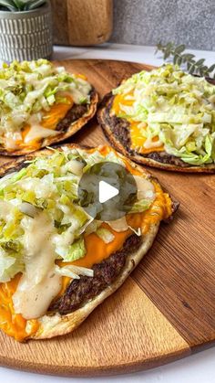 three pizzas with cheese, lettuce and sauce on them sitting on a cutting board