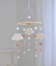 a baby crib mobile with white, pink and brown clouds hanging from it's sides