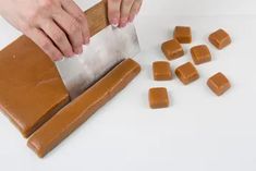 a person is cutting up some food on a white table with chopping board and pieces of chocolate