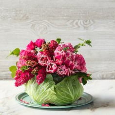 a vase filled with pink flowers sitting on top of a wooden table next to a white wall