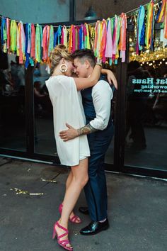 a man and woman hugging each other in front of a building with colorful streamers