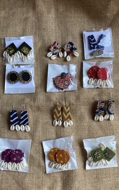 nine pairs of earrings are on display in plastic bags and lined up against a bed sheet