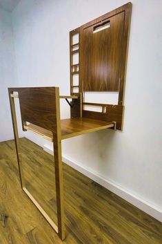 a wooden desk with an open drawer on the top and shelf below it, against a white wall