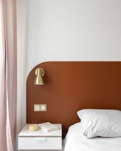 a white bed sitting next to a brown wall