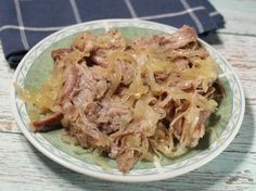 a white plate topped with meat and onions on top of a blue and white table