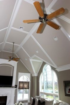 a living room with a ceiling fan and large windows