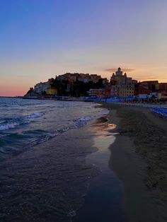 the beach at sunset with buildings in the background