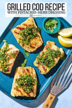 grilled chicken with pesto - herb dressing on a blue platter next to lemon wedges