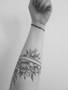 a black and white photo of a woman's arm with a flower tattoo on it