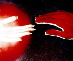 two hands touching each other on a black surface with red and white colors in the background