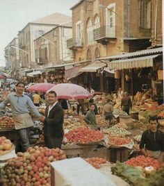 an outdoor market with people shopping and selling fruits, vegetables and other things in the background