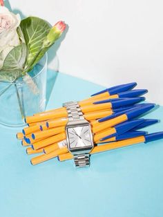 a bunch of pencils sitting on top of a table next to a vase filled with flowers