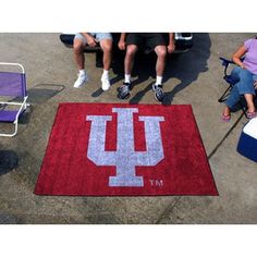 the university of indiana rug is on the ground next to two people sitting in lawn chairs