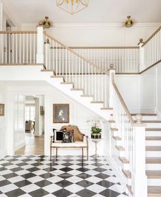 a white staircase with black and white checkered flooring in a home's entryway