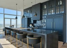 a kitchen with an island and bar stools in front of large windows overlooking the city