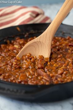 a wooden spoon stirring chili in a skillet